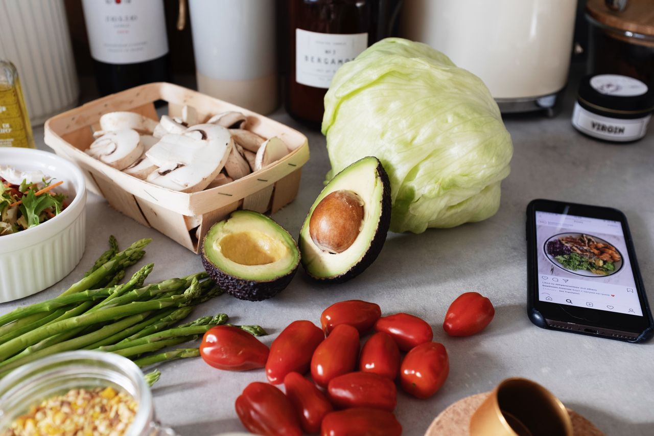 who-we-are Fresh organic chopped vegetables placed on countertop near kitchen utensils and mobile phone in bright kitchen during preparation salad according to recipe from smartphone